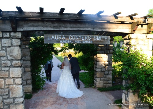Newlyweds walk under a pergola at the Laura Conyers Smith Municipal Rose Garden in Kansas City, a popular spot for weddings.